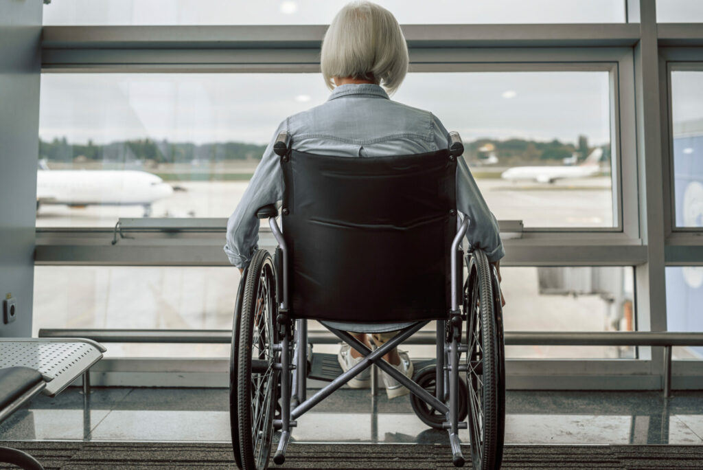 Accessibility Tourism: Elderly woman is using a wheelchair in lobby before flight