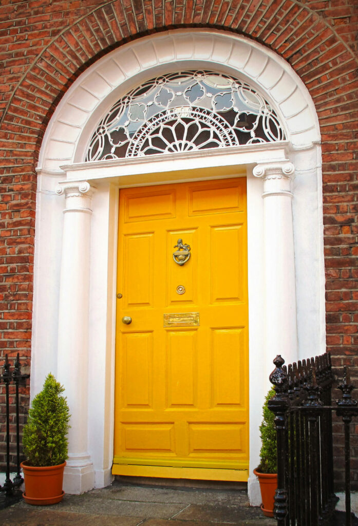 Georgian door in Dublin, Ireland. The door is bright yellow, with an intricate fanlight window above.