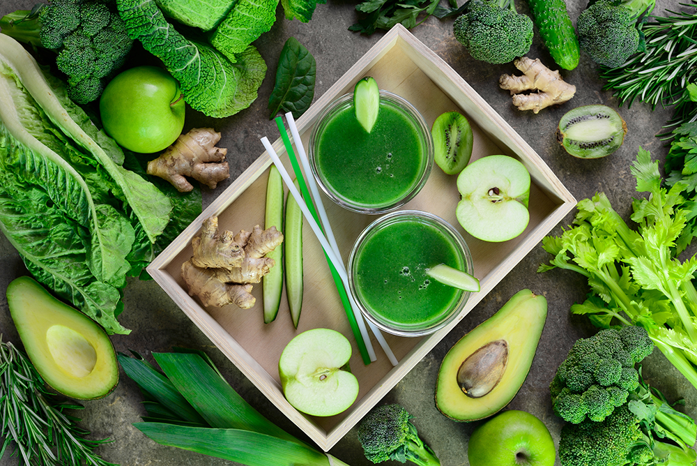 Wellness Detox green smoothies concept, two glasses of green diet detox drink  and various fresh green vegetables around them, view from above composition